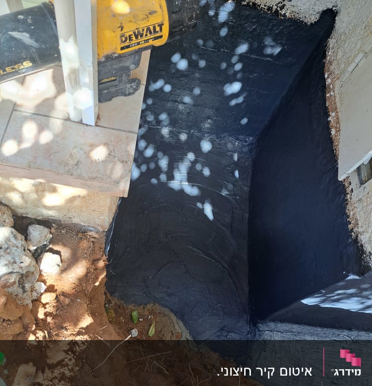 קיר אטום עם חומר איטום שחור וכלי עבודה